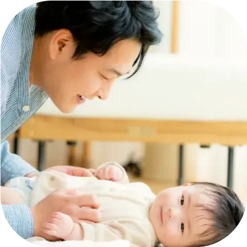 ベビーベッドに寝ている赤ちゃんをあやすパパ