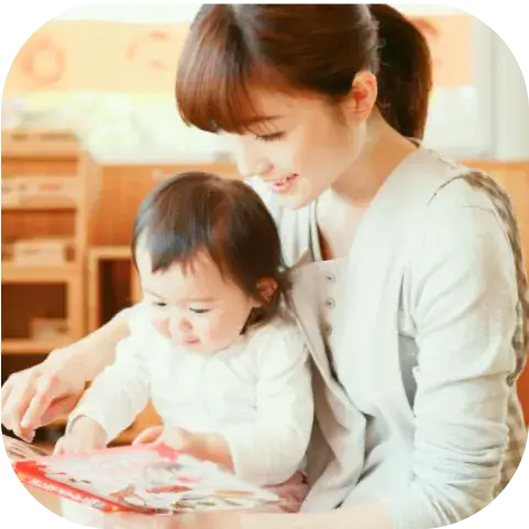 膝に子どもを乗っけながら一緒に絵本を読んでいるママ
